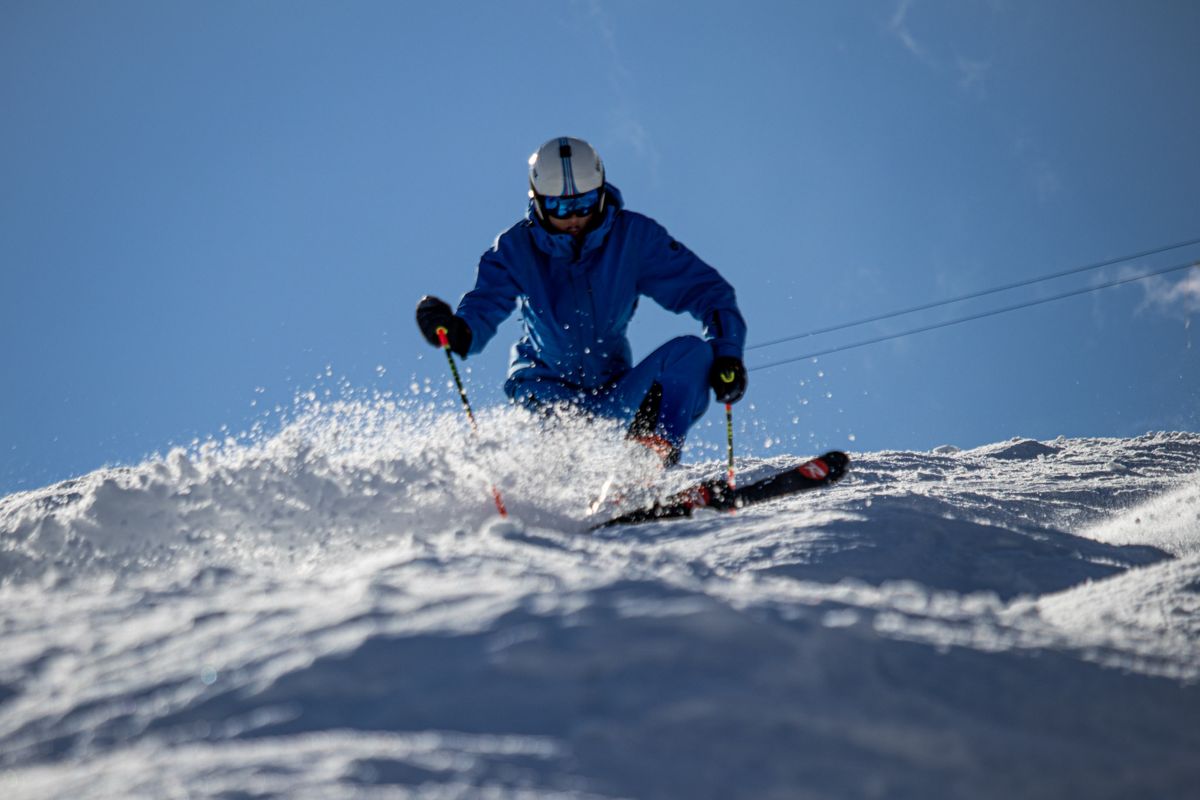 Skier in blue carving through powder toward the camera