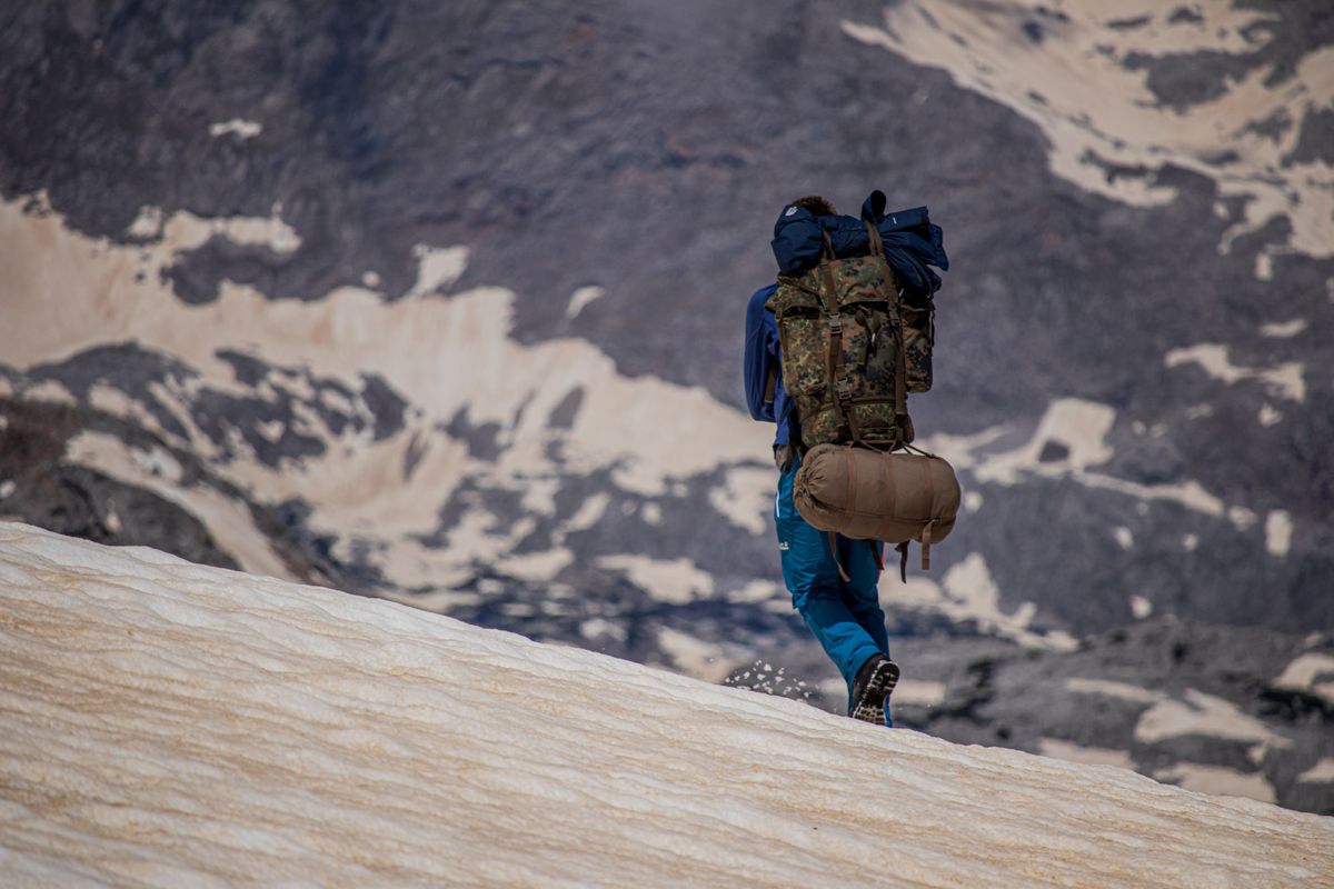 Hiker with a large pack crossing a snowfield