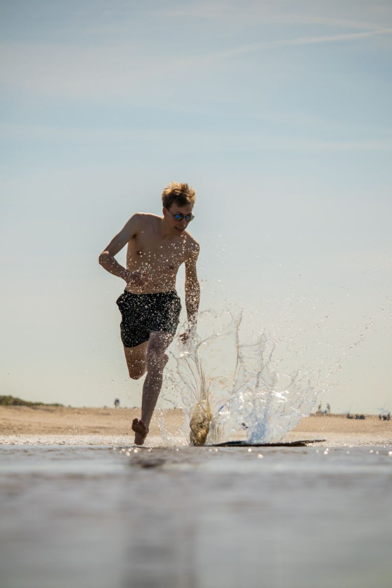Runner splashing through shallow water on a beach