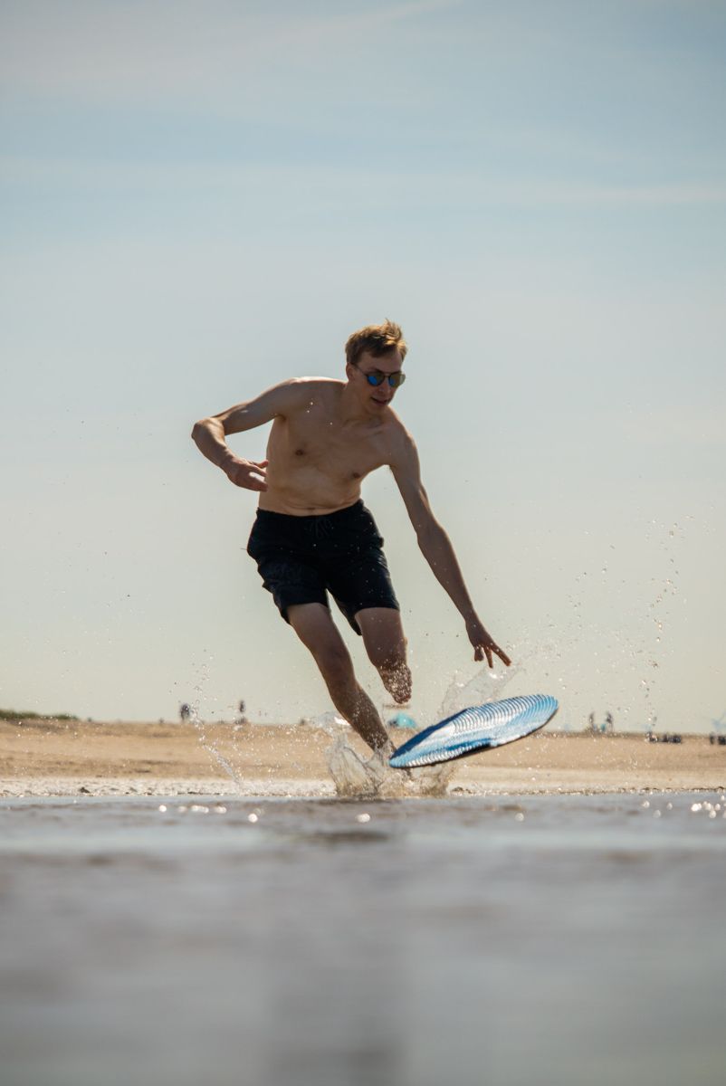Skimboarder dropping his board into the shallows