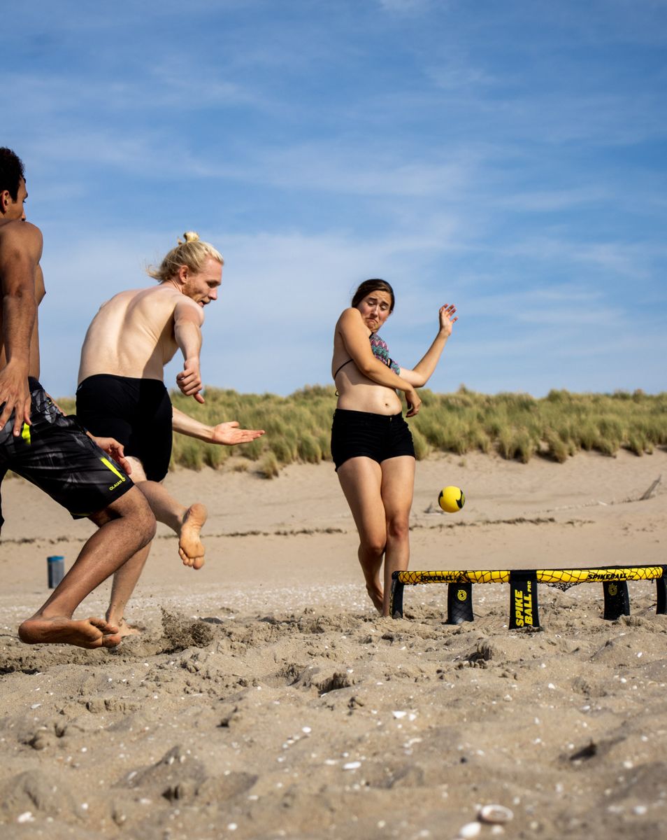 Spikeball players diving for the ball on a beach