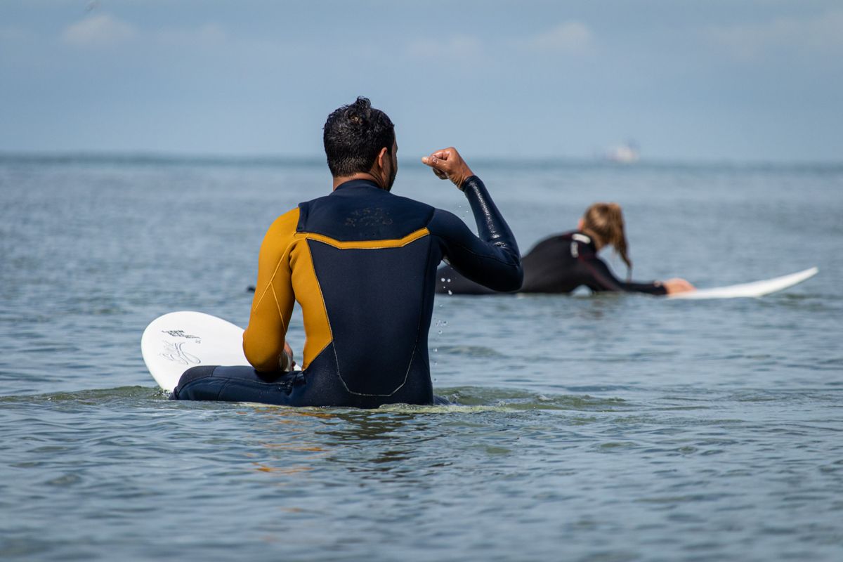 Surfer sitting on his board, raising a fist