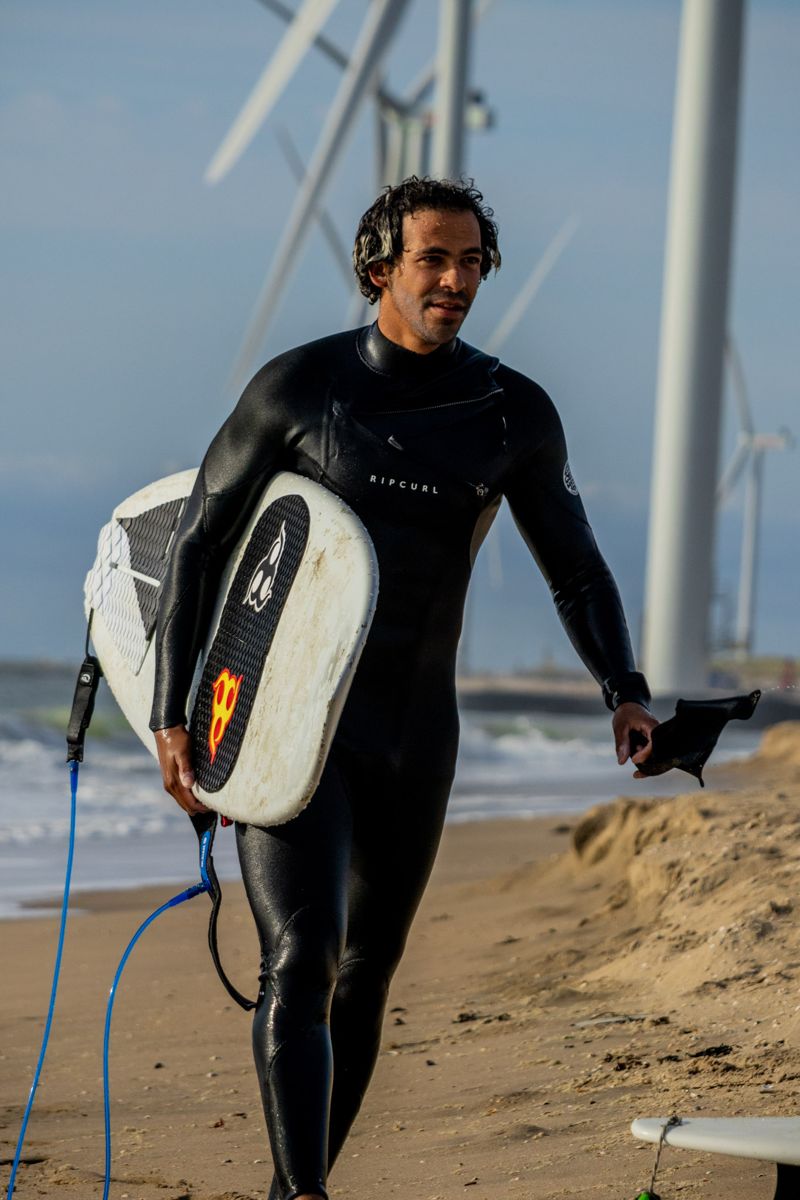 Surfer walking out of the sea with his board