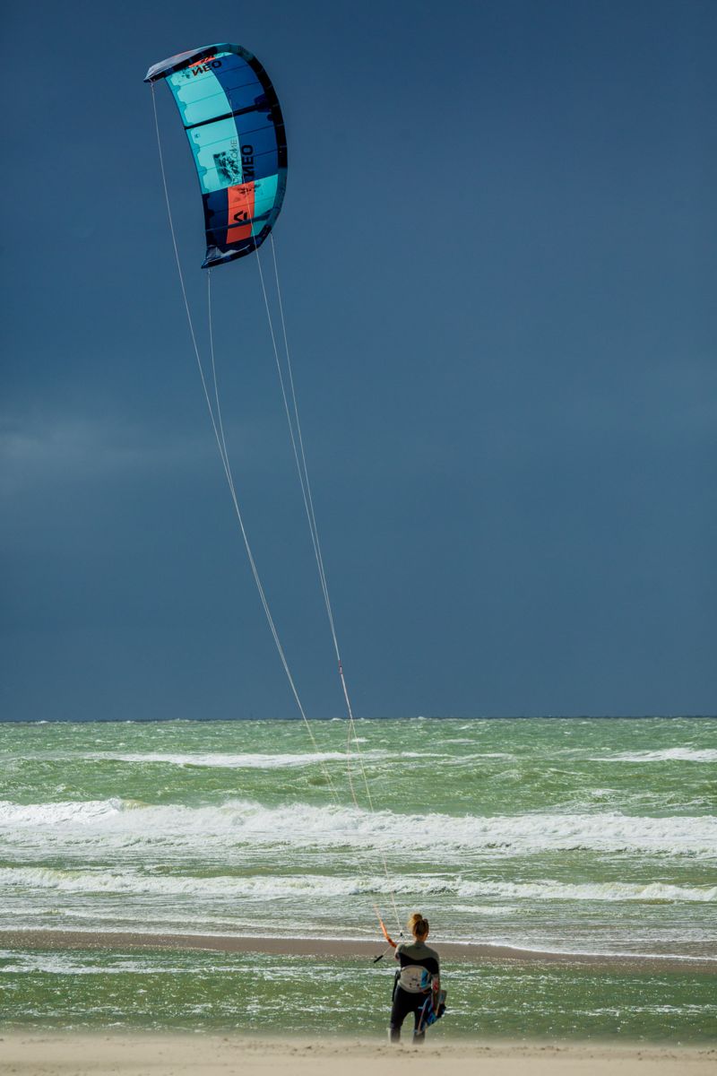 Kitesurfer launching under a dark storm sky