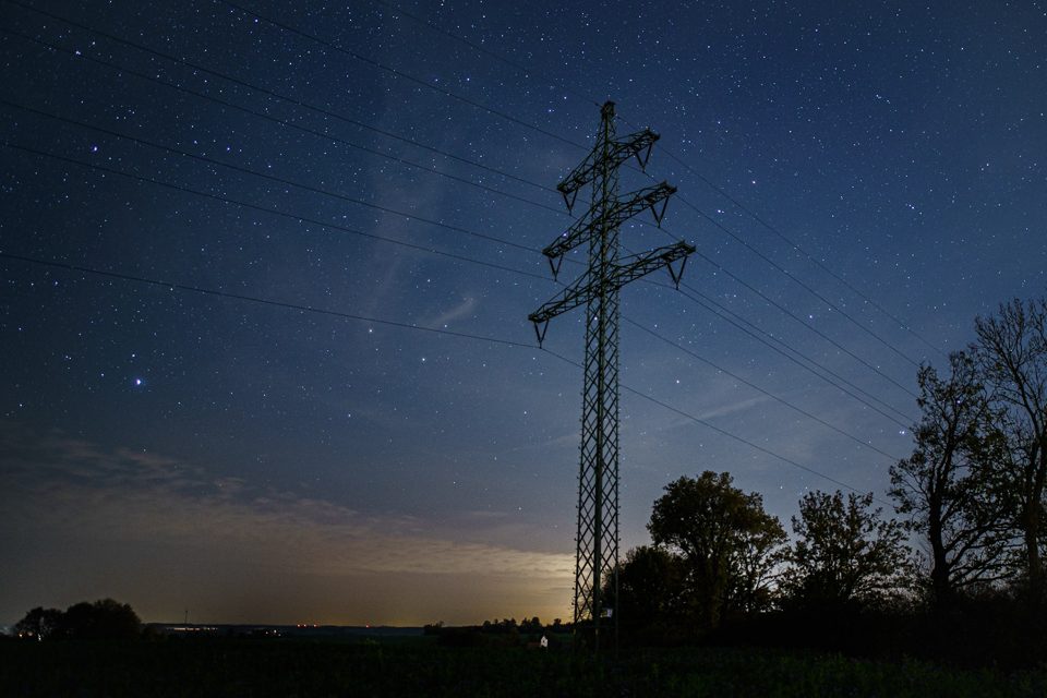 Power pylon against a starry night sky