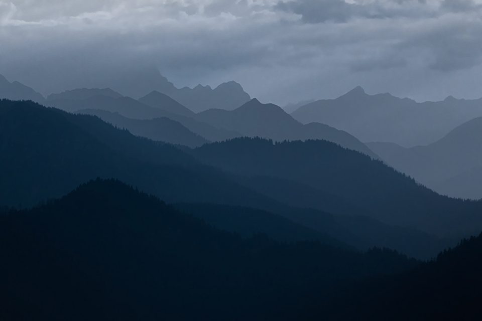 Layered blue mountain ridges under heavy clouds